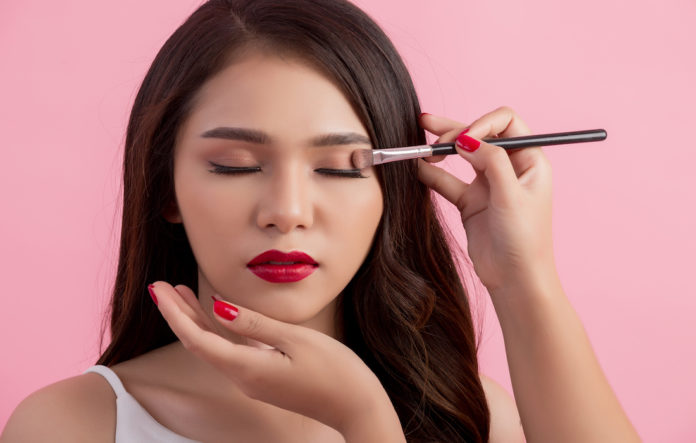 Make-up artist applying liquid eyeliner with brush, close up